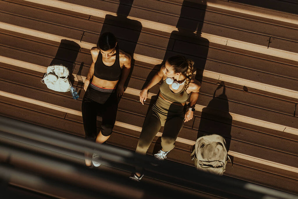 Por encima de la vista en las mujeres jóvenes y bonitas toma un descanso después de correr en el área urbana - Foto, Imagen