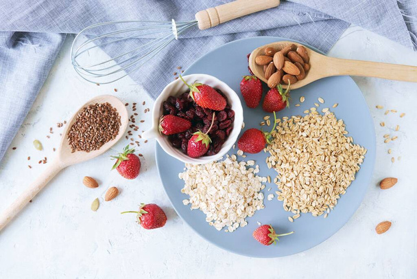 Свежая клубника на тарелке, орехи и семена, на фоне серой льняной ткани, здоровые ингредиенты для завтрака - Фото, изображение