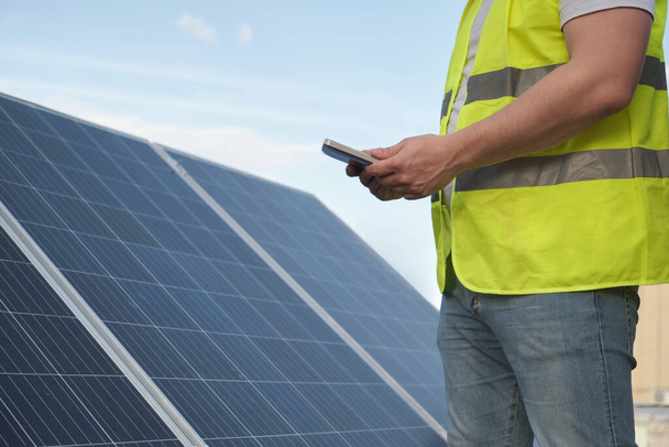 Technicien méconnaissable utilisant une tablette pour contrôler la centrale solaire photovoltaïque. Énergie écologique verte. - Photo, image