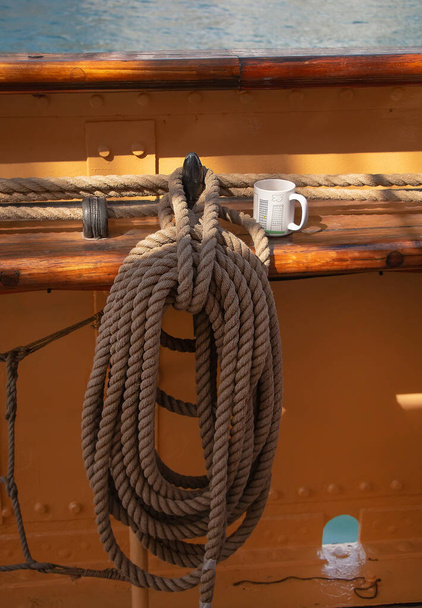 Paquete de cuerda para controlar las velas sobre el fondo de la tabla del yate y una taza blanca para el té, la vida en un barco, elementos de un barco de vela - Foto, Imagen