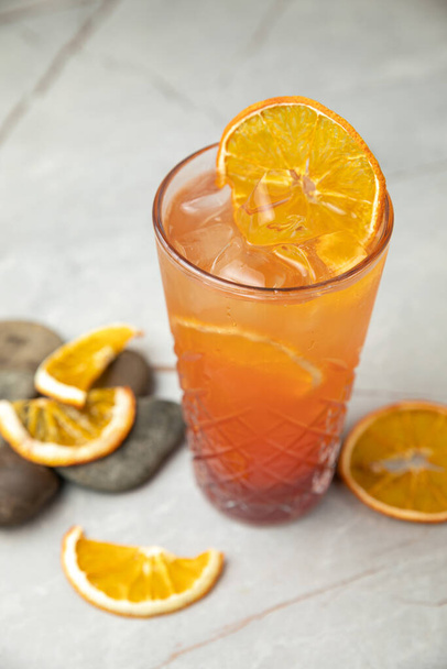 orange juice with lemon and ice cubes on a wooden background - Fotó, kép