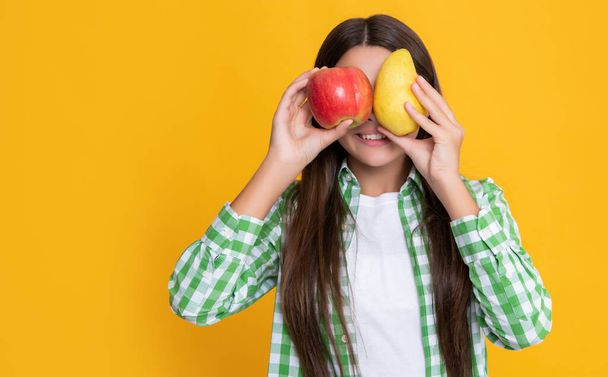 happy girl with fresh apple and pear on yellow background. - Valokuva, kuva