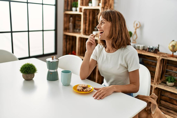 Young caucasian woman having breakfast sitting on table at home - Photo, image