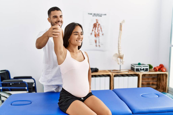 Latin man and woman wearing physiotherapist uniform having pregnancy rehab session at physiotherapy clinic - Fotografie, Obrázek