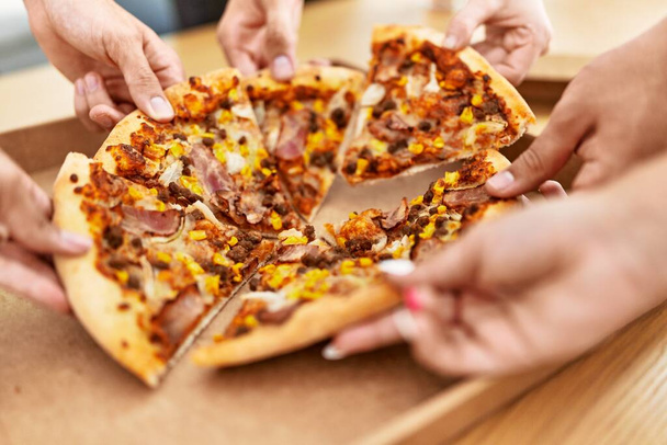 Руки людей, принимающих порцию итальянской пиццы на столе дома. - Фото, изображение