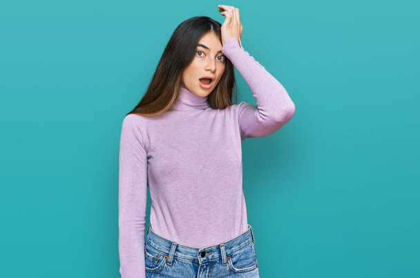 Young beautiful teen girl wearing turtleneck sweater surprised with hand on head for mistake, remember error. forgot, bad memory concept.  - Fotoğraf, Görsel