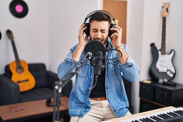 Giovane uomo ispanico cantare canzone in studio di musica - Foto, immagini