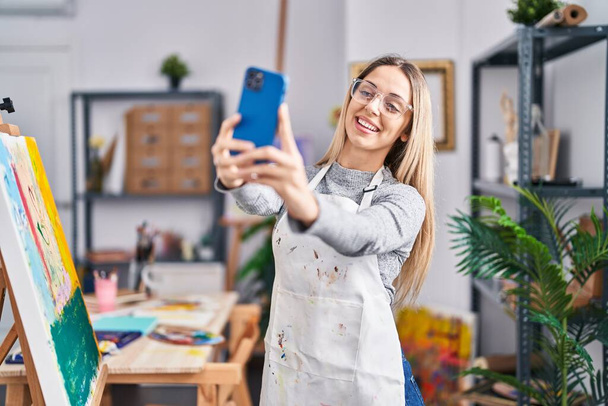 Giovane artista donna sorridente fiducioso facendo selfie dallo smartphone in studio d'arte - Foto, immagini