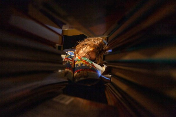 Μια αγχωμένη γυναίκα που σπουδάζει σε μια βιβλιοθήκη για τις τελικές εξετάσεις της. - Φωτογραφία, εικόνα