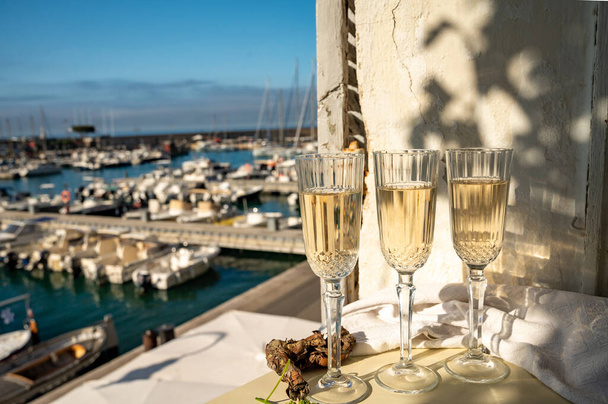 Three glasses of French champagne sparkling wine and view on colorful fisherman's boats in old harbour in Cassis, Provence, France, summer party in Provence - Фото, зображення