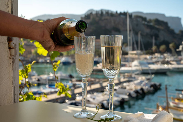 İki bardak Fransız şampanyası, köpüklü şarap ve renkli balıkçıların Cassis, Provence, Fransa 'da eski bir limandaki teknelerine manzarası, Provence' de yaz tatili. - Fotoğraf, Görsel