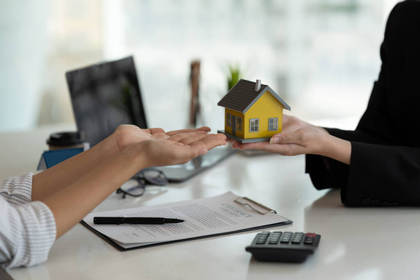 Les agents immobiliers acceptent d'acheter une maison et de donner le modèle de maison aux clients à leurs bureaux d'agence. Accord conceptuel. - Photo, image