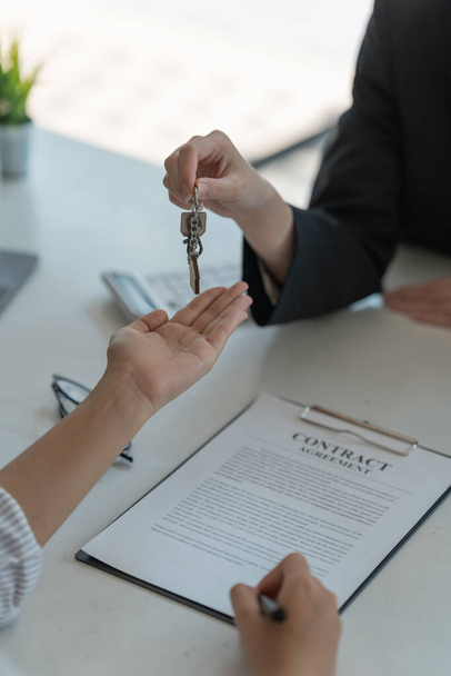 real estate agent holding house key to his client after signing contract agreement in office,concept for real estate, moving home or renting property. - Photo, Image