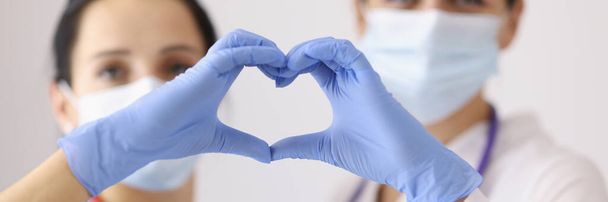 Enfócate en los cardiólogos que muestran el símbolo del corazón con las manos en guantes. Enfermedades cardíacas, donación de órganos e idea de atención médica. Cardiología, medicina y concepto de salvar vidas - Foto, Imagen