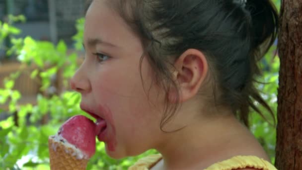 Petite fille regardant la caméra tout en mangeant de la crème glacée. - Séquence, vidéo