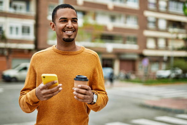 Young african american man using smartphone drinking coffee at the city. - Φωτογραφία, εικόνα