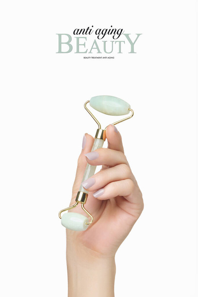 Publicidad de belleza y cuidado de la piel con rodillo de jade en mano femenina cuidada aislada en blanco con espacio para copiar. Formato vertical - Foto, Imagen