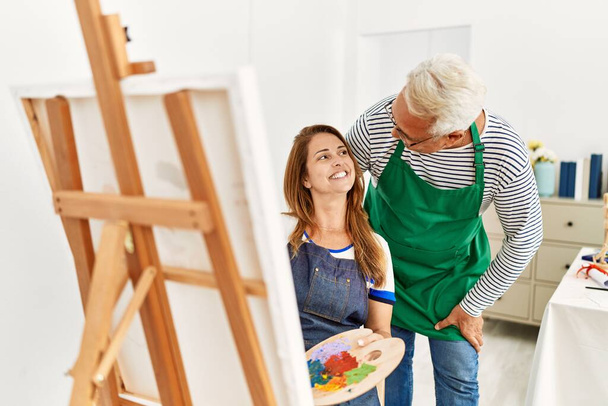 Двоє художників середнього віку посміхаються щасливого живопису в художній студії
. - Фото, зображення