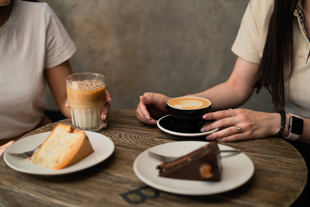 two girls are sitting in a cafe and holding coffee - Photo, Image