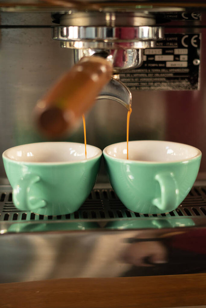 Two cups of coffee being poured from a espresso machine. - Фото, изображение