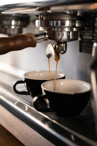Two cups of coffee being poured from a espresso machine. - Zdjęcie, obraz