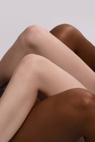 Be different. Plexus of female legs. Graceful female legs, knees touch each other isolated on grey studio background. Concept of diversity, unity, love, support. Human rights, choice and equality - Foto, imagen