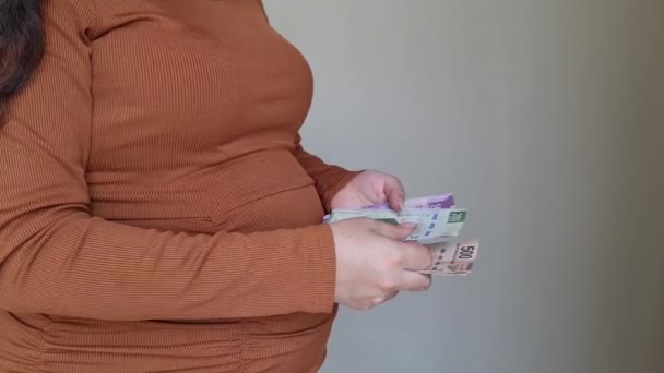 manos de una mujer embarazada sosteniendo y contando billetes mexicanos - Imágenes, Vídeo
