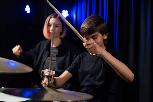 Young woman teaching boy to play drums - Photo, Image
