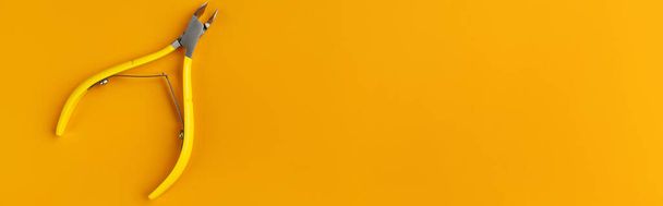 Flache Lageansicht gelbe Haarschneidemaschinen für Maniküre-Pediküre auf orangefarbenem Hintergrund. Vorlage für Schönheitssalon mit Kopierraum - Foto, Bild