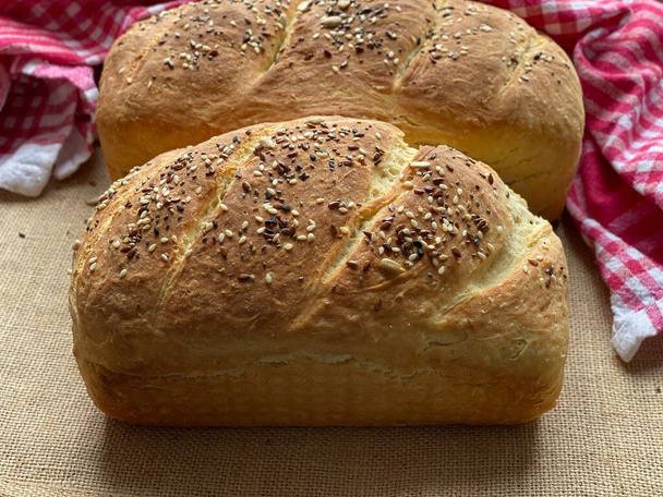 Hausgemachtes Brot mit Leinsamen gebacken. Vollkorngebäck im Sortiment liegt auf dem Tisch. - Foto, Bild