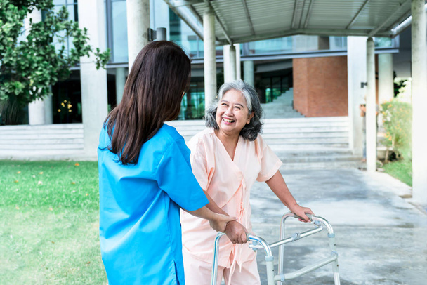 Asiática anciana paciente feliz y sonrisa, mientras que el médico de la mano, animado y apoyado a ella, Que sostiene un bastón, hacer fisioterapia para caminar, concepto de atención médica y la osteoartritis. - Foto, Imagen