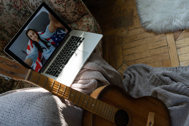 little kid playing acoustic guitar and watching online course on laptop while practicing at home - Photo, Image