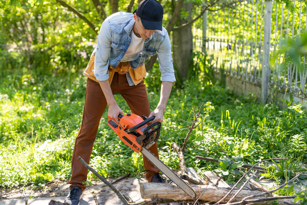 Az ember láncfűrésszel fűrészeli az ágakat. A professzionális fakitermelés fogalma. - Fotó, kép