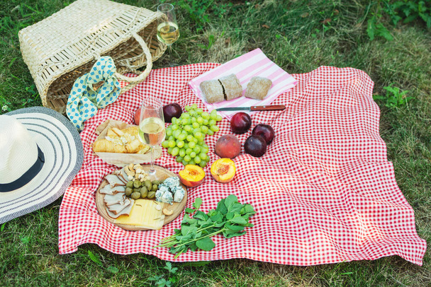 Καλοκαιρινό πικνίκ στο πάρκο στο γρασίδι. Κρασί, φρούτα και κρουασάν. - Φωτογραφία, εικόνα