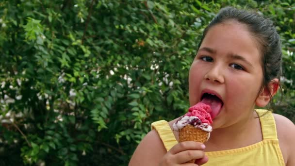 Malá dívka při pohledu na kameru při jídle zmrzliny záběry. - Záběry, video