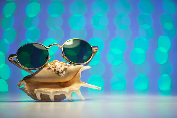 Retro sluneční brýle s shell a rozmazaný lesklé barevné pozadí - Fotografie, Obrázek