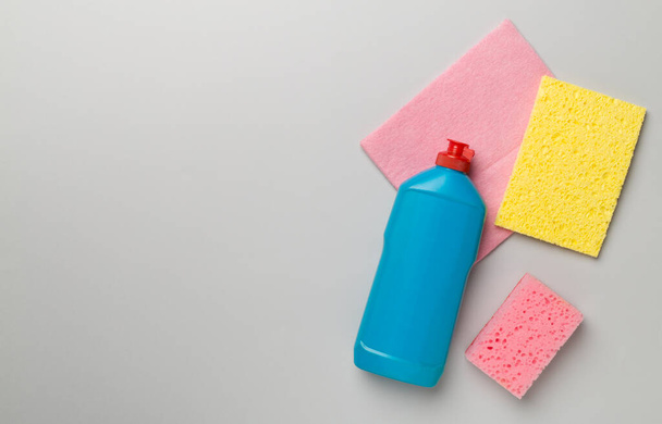 Пляшка з миючим засобом для посуду та губками на кольоровому фоні, вид зверху
. - Фото, зображення