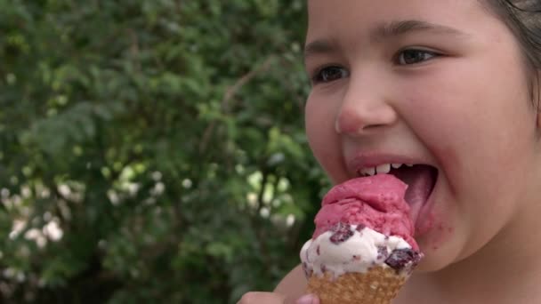Malá dívka usmívající se při pohledu na kameru při jídle zmrzliny záběry. - Záběry, video