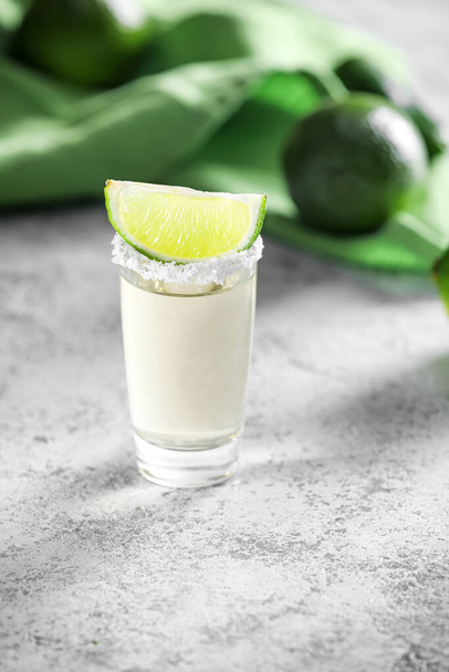Shot of tasty mexican tequila with lime on grey background - Фото, изображение