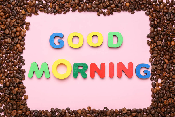 Samenstelling met tekst GOED MORNING en koffiebonen op roze achtergrond, close-up - Foto, afbeelding