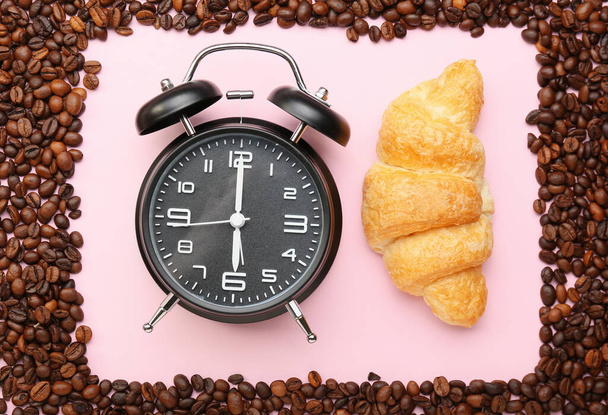 Samenstelling met koffiebonen, croissant en wekker op roze achtergrond, close-up - Foto, afbeelding