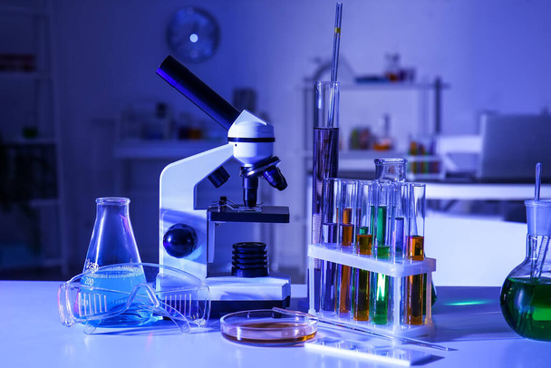 Χημικά γυάλινα σκεύη και μικροσκόπιο στο τραπέζι στο ιατρικό εργαστήριο - Φωτογραφία, εικόνα