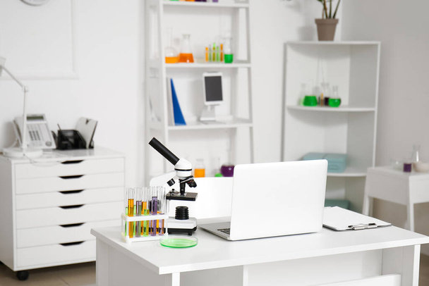 Moderno posto di lavoro, microscopio, vetreria chimica e laptop in laboratorio medico - Foto, immagini