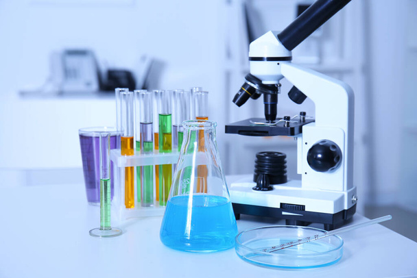 Microscopio moderno y cristalería química en la mesa en laboratorio médico - Foto, Imagen