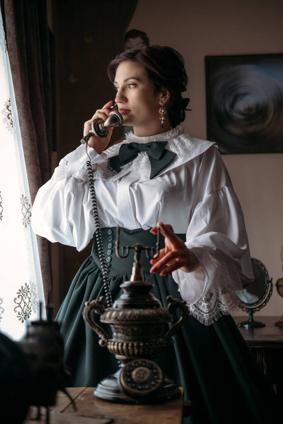 Beautiful woman in vintage blouse costume with retro phone. Edwardian Victorian Epoque dress 1800s early 1900s clothing in old interior. Historical dresses, vintage outfits, beautiful retro dress - Photo, Image