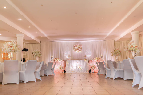 festliche Tischdekoration mit Kristallleuchtern, goldenen Kerzenleuchtern, Kerzen und weiß-rosa Blumen. Stilvoller Hochzeitstag. - Foto, Bild