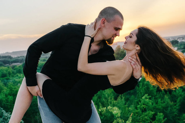 mies ja nainen mustissa vaatteissa halaamassa auringonlaskun aikaan - Valokuva, kuva