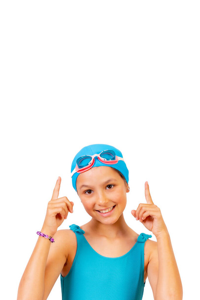 Girl with swimsuit and diving goggles, swimming lessons in the pool, pointing up. white background with copy space - Foto, Imagem
