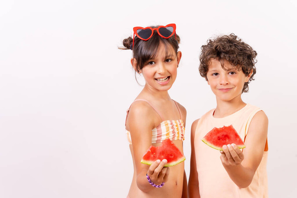 Caucasian children eating a watermelon in the summer heat, school vacation concept. White background - Фото, зображення