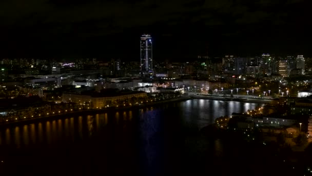 Näkymä drone.Stock footage.Kaunis kaupunki yöllä sijaitsee joen vieressä ja kauniita korkeita uusia rakennuksia ja toimistoja ja rauhallinen valaistu tie. Laadukas 4k kuvamateriaalia - Materiaali, video
